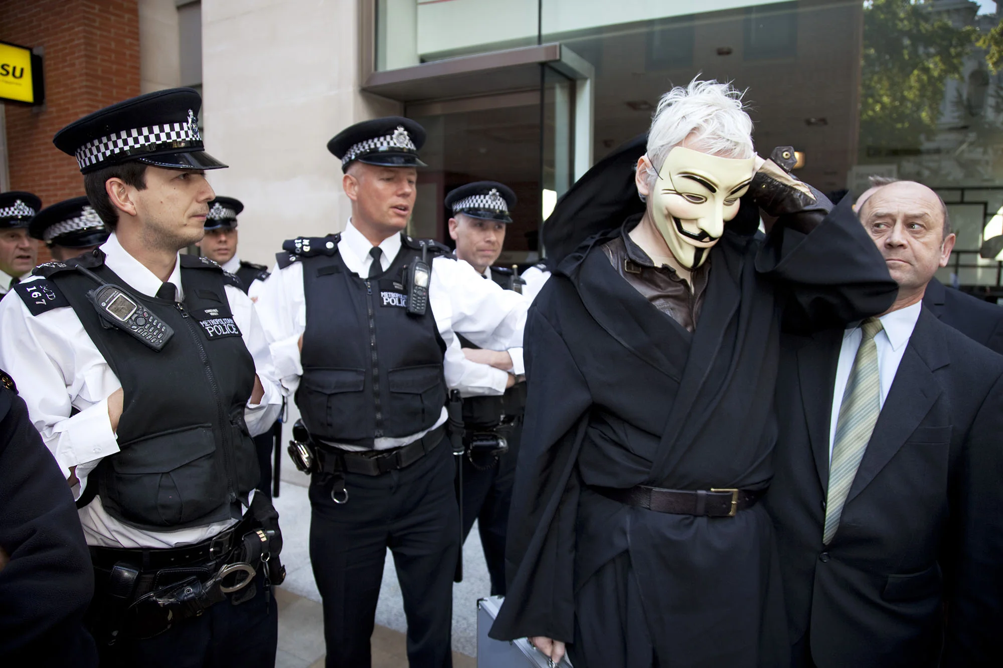 Julian Assange is de-masked and questioned by police during the Occupy London demonstration.