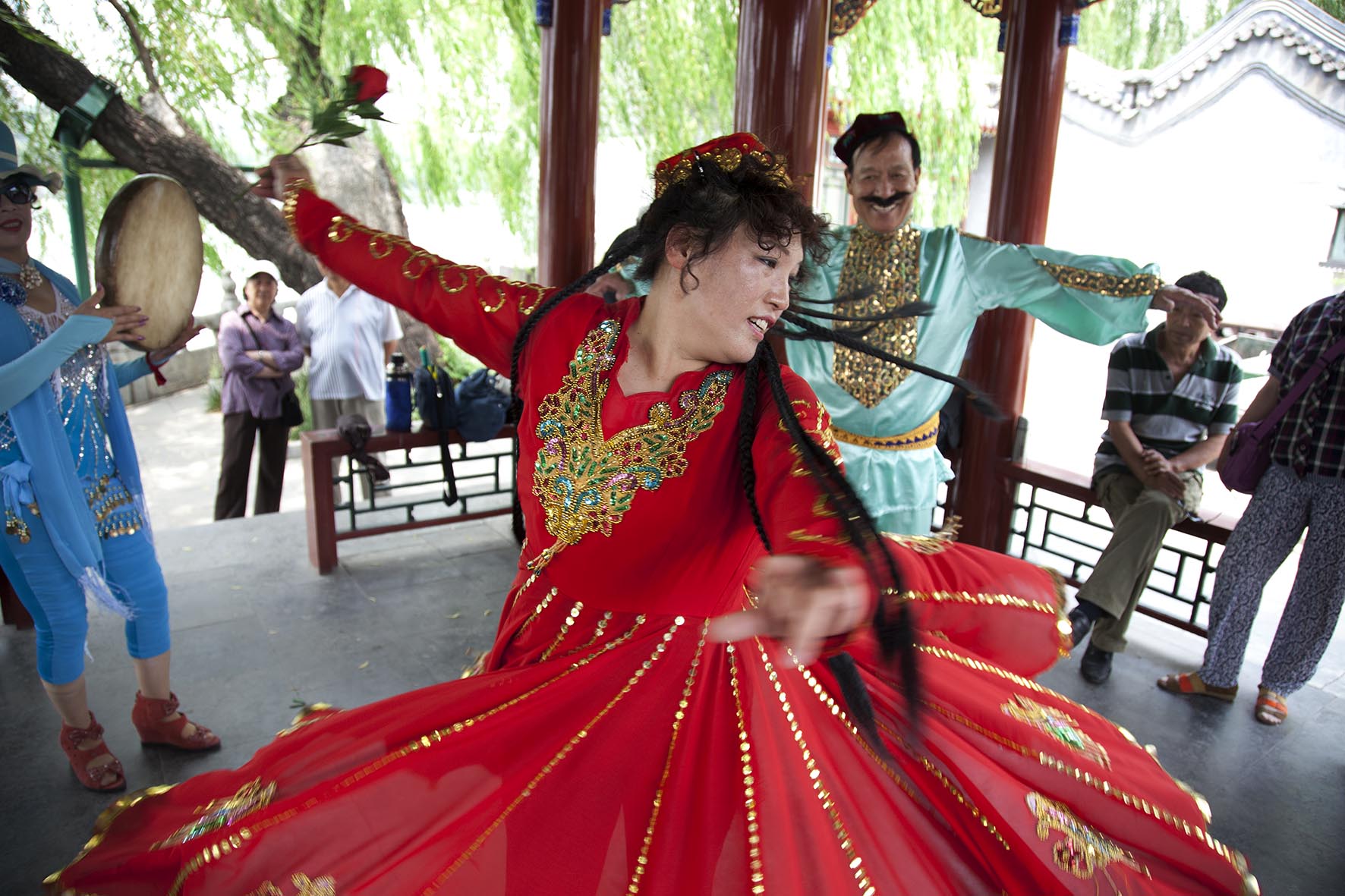  People dressed in traditional clothing dance together in a form which also tells a story in Beihai Park. 