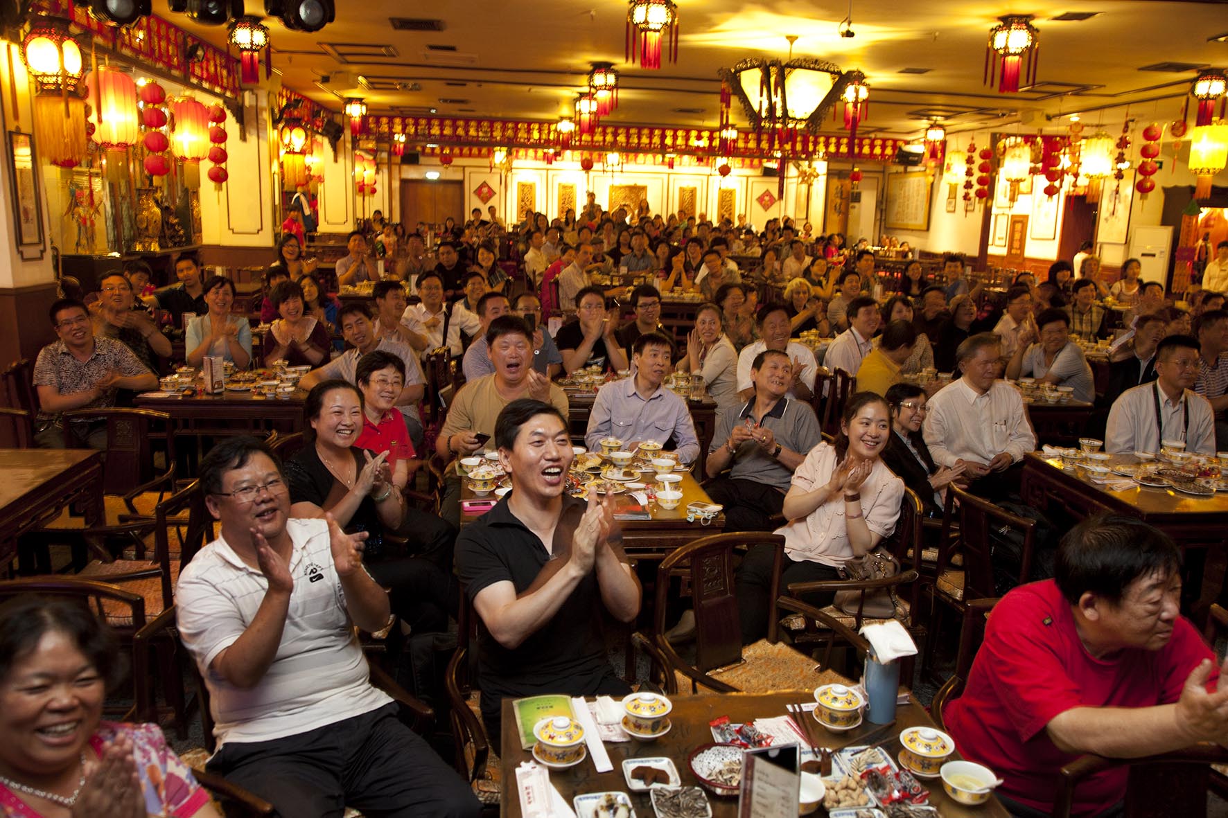  Customers sit enjoying the show, applauding and shouting at Laoshe teahouse 