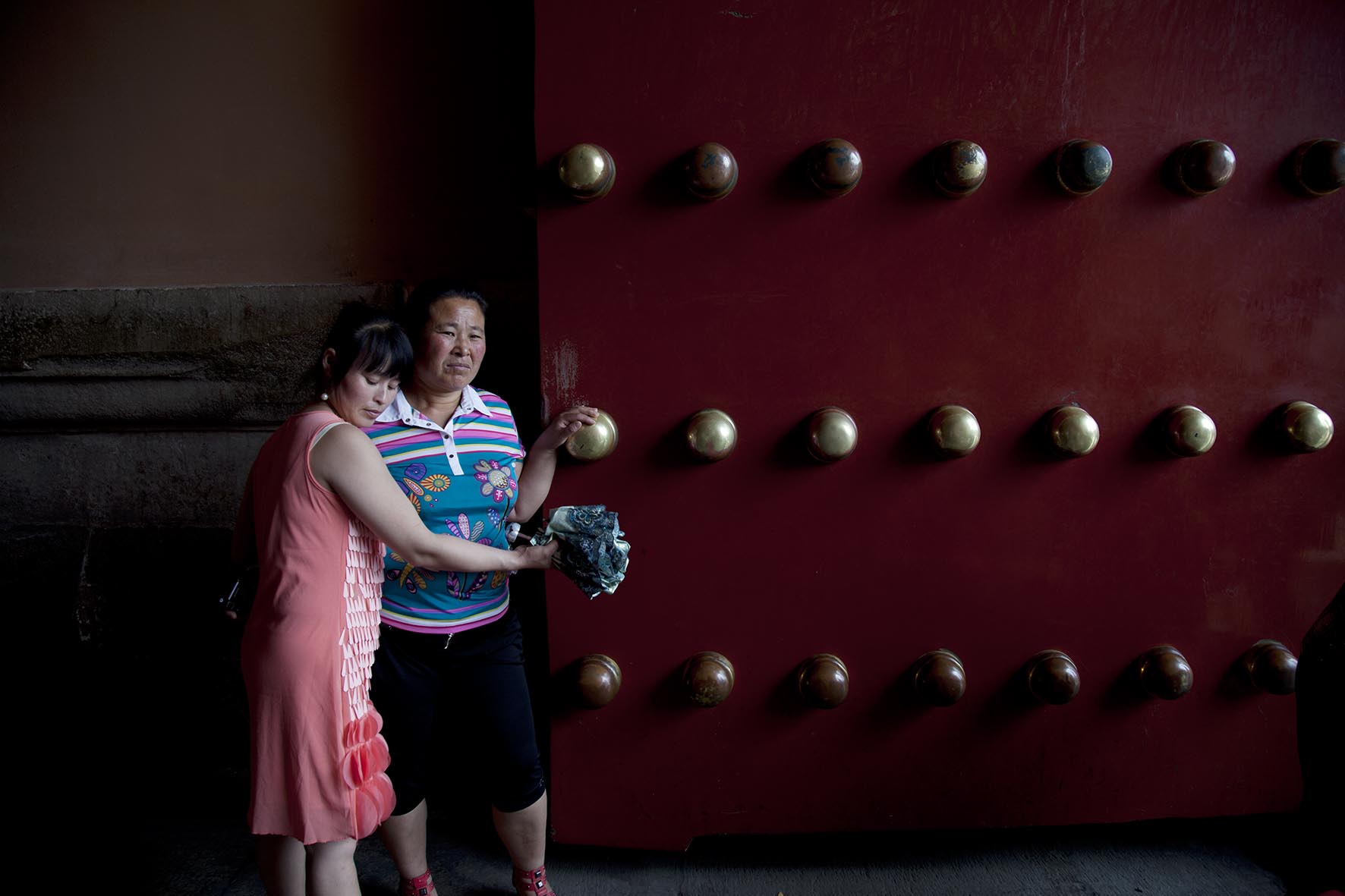  Chinese tourist hugs her mother as she touches the large brass studs on one of the doors inside The Forbidden City. 