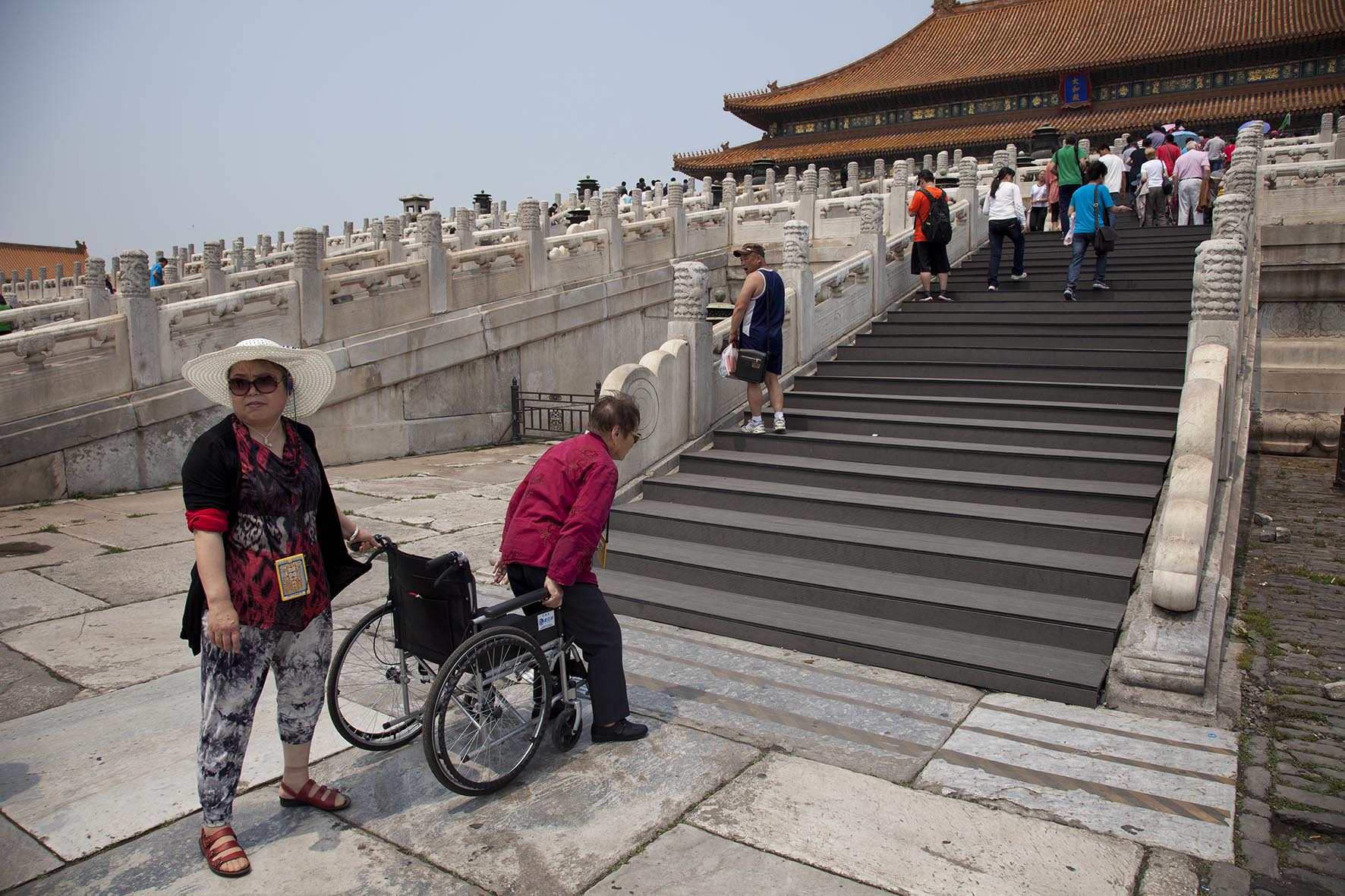  Elderly woman gets up from her wheelchair to climb the steps to the Hall of Supreme Harmony inside The Forbidden City, Beijing. 