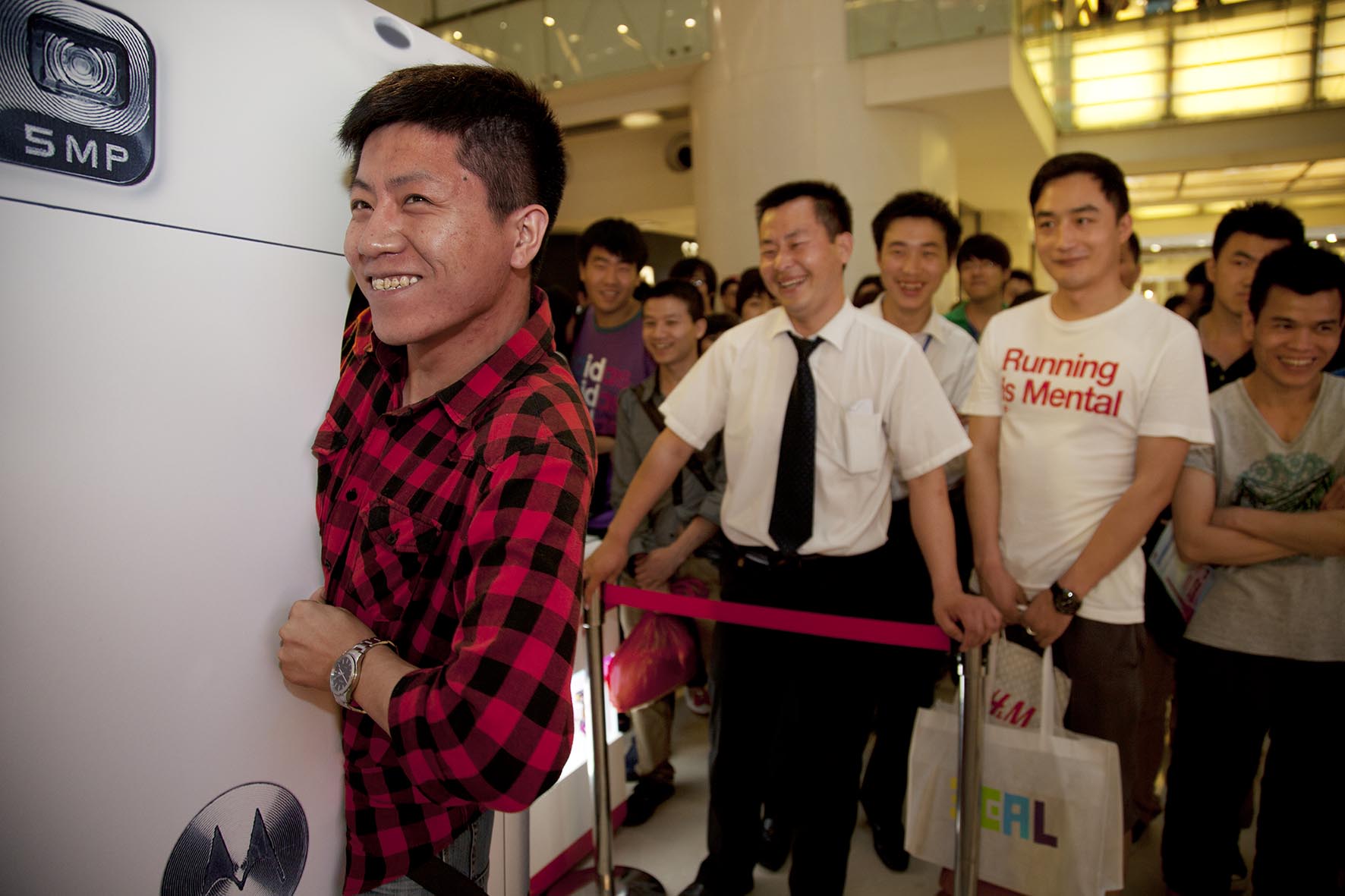  Man squeezes through a large model Motorola cell phone in order to win a handset. Skinny winners at Joy City shopping mall. 