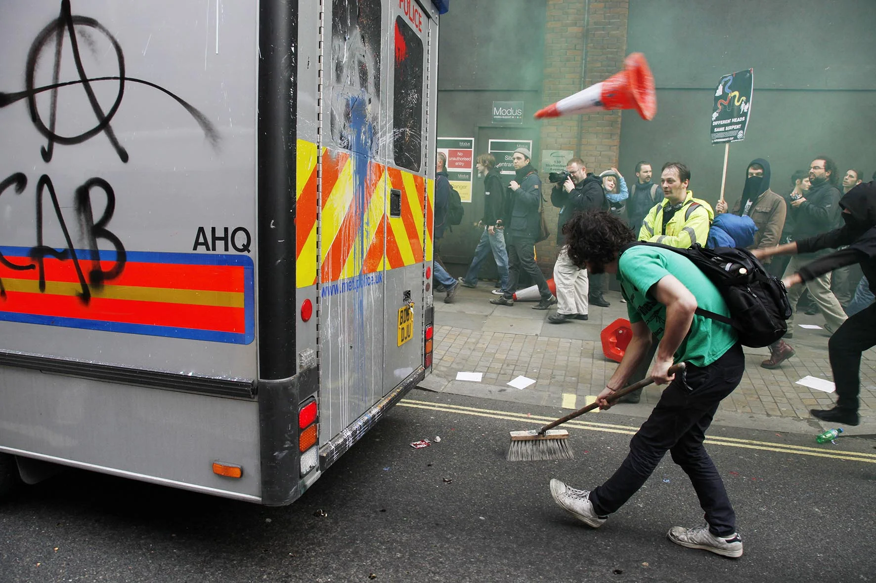 Protester pretending to sweep up during an attack on a police vehicle as anti capitalists go on the rampage through central London.