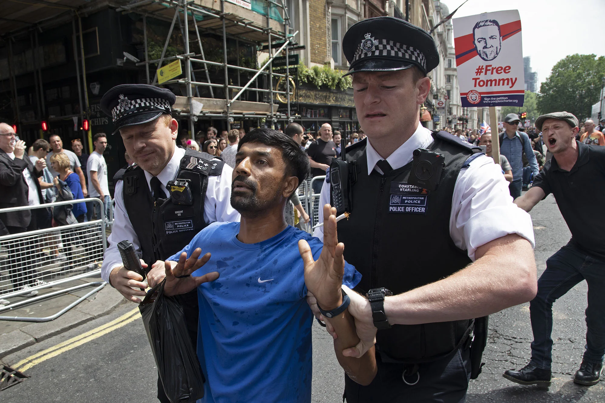 One protester is led away for his own safety by police as he is goaded by a Tommy Robinson supporter during the Democratic Football Lads Alliance 'day of freedom'.