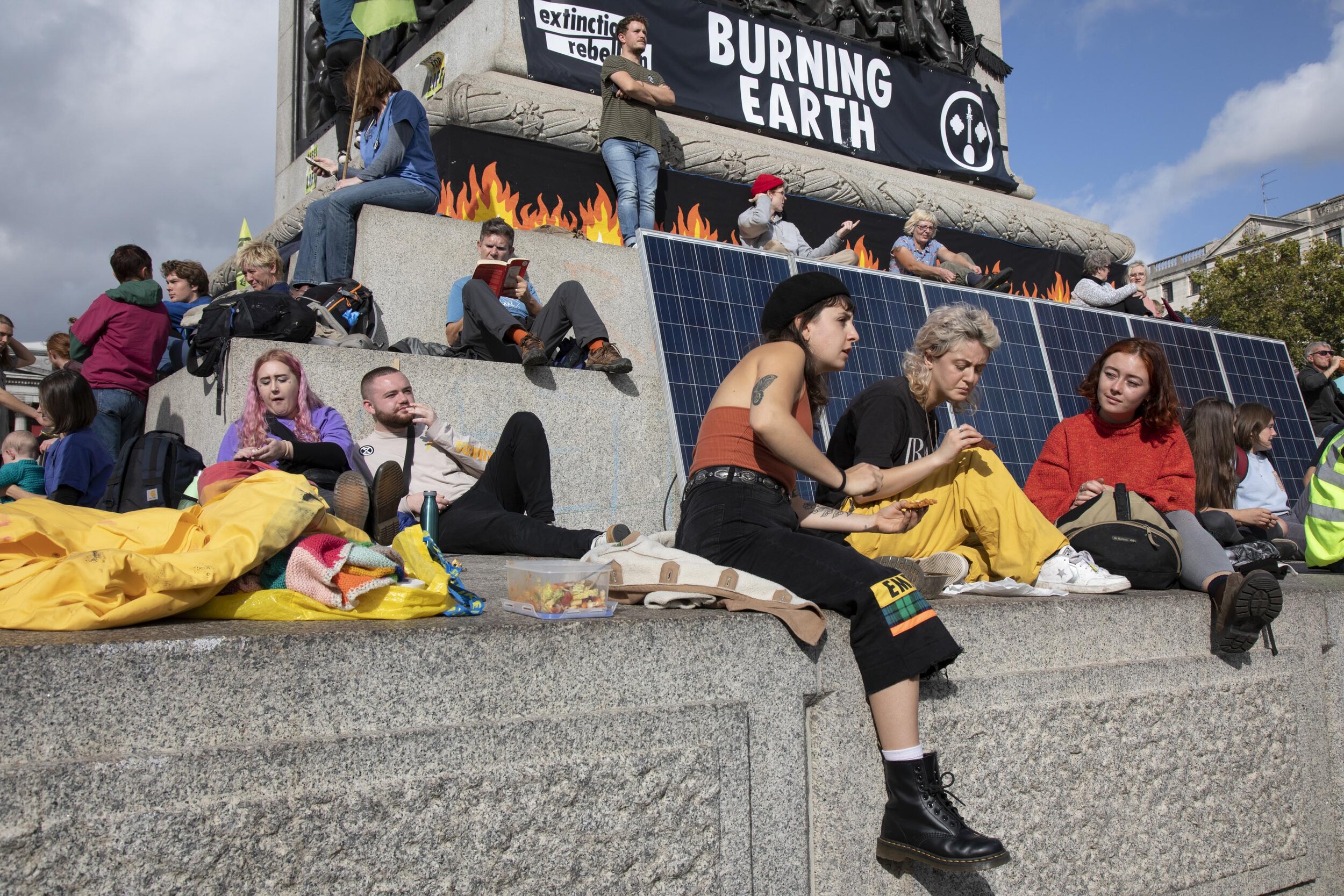  Climate change activists sit at the base of Nelson's Column in Trafalgar Square surrounded by solar panels which are powering activities in the area. 