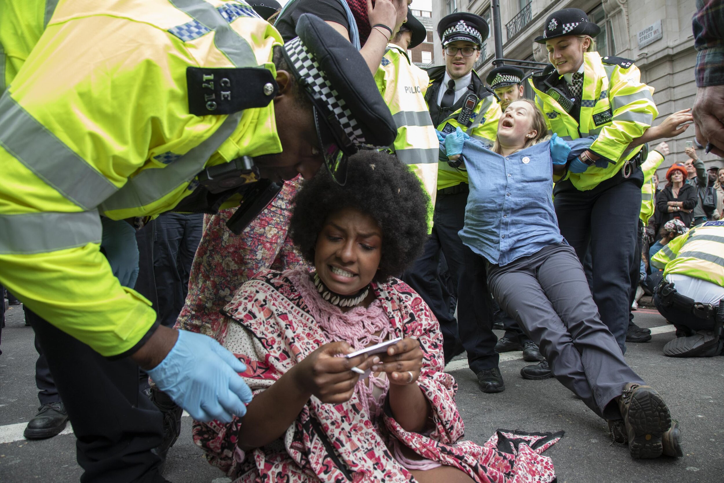  Police speak to one protester, as she asks them to explain a section 14 notice in detail as they arrest and remove another while clearing climate change activists at Oxford Street. 
