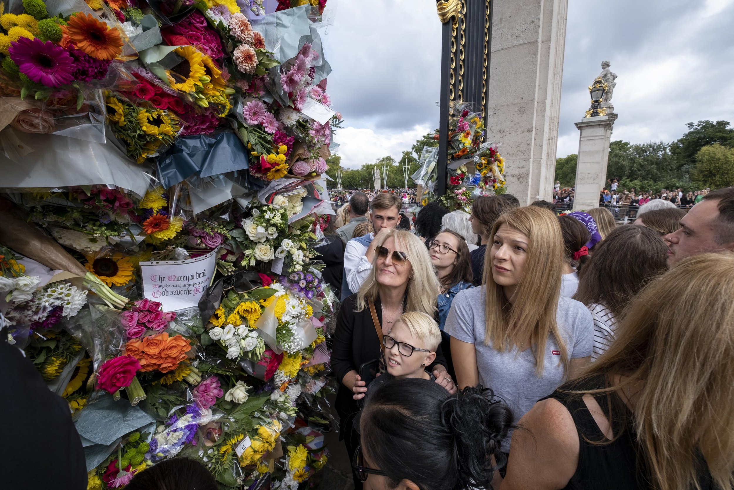  Crowds of people begin to leave flowers in the gates surrounding Buckingham Palace. 