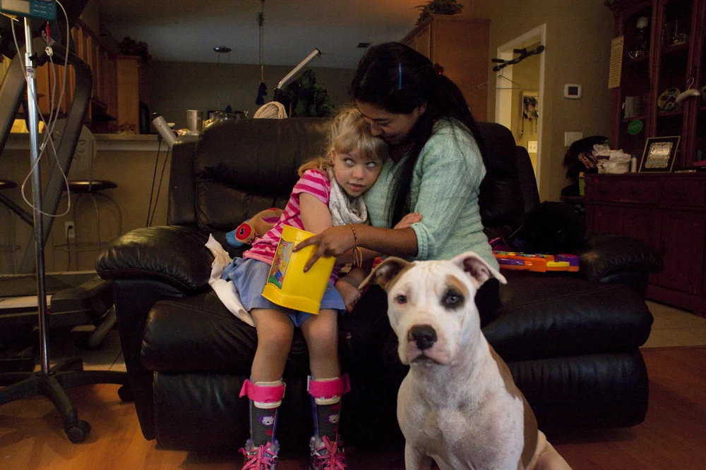 Christina cuddles with Angie, her caregiver, and her dog Bella. Jacksonville, FL