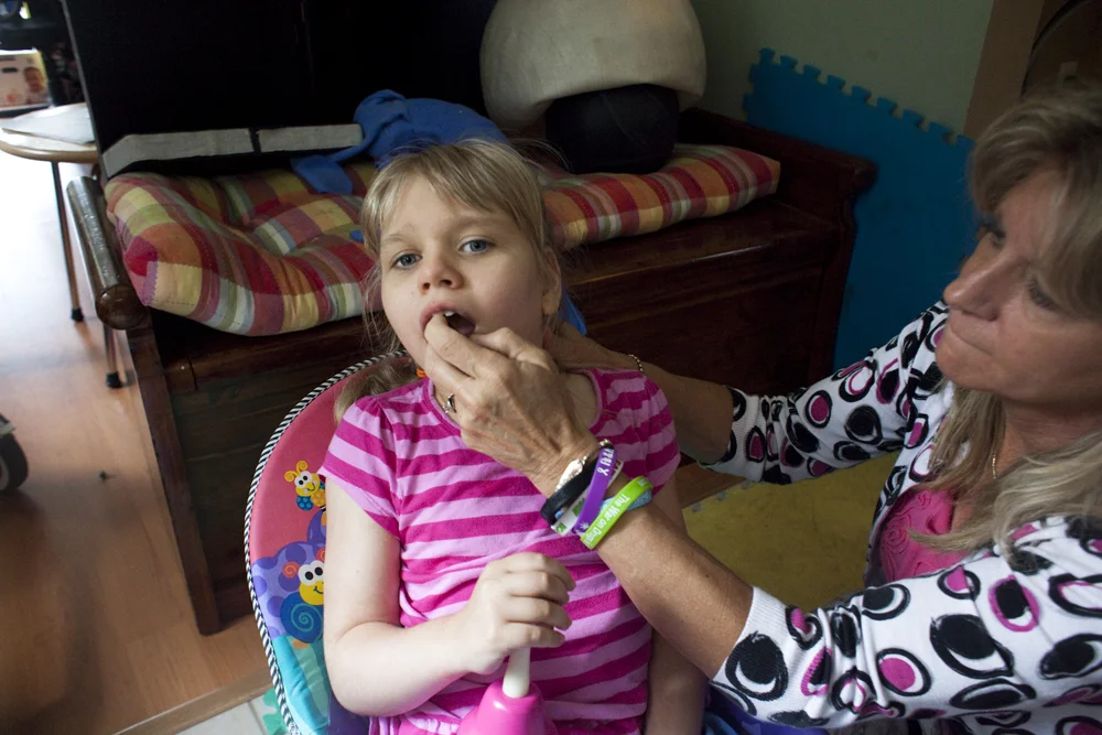 Anneliese Clark gives her daughter Christina one dose of medical cannabis concentrate infused with coconut oil, by spraying two times into her mouth. Jacksonville, FL