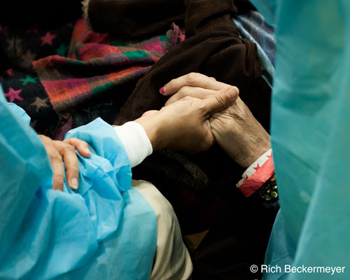 One-of-the-last-dental-patients-listens-to-a-ukalele,-surrounded-by-3-volunteers-to-help-calm-her-down-from-a-stressful-extraction.jpg