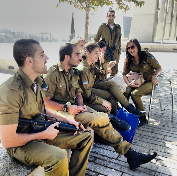 Israeli military hanging out with a machine gun in a public square in Jerusalem.