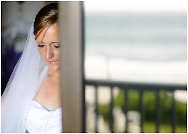 bride having dress adjusted in doorway reflection