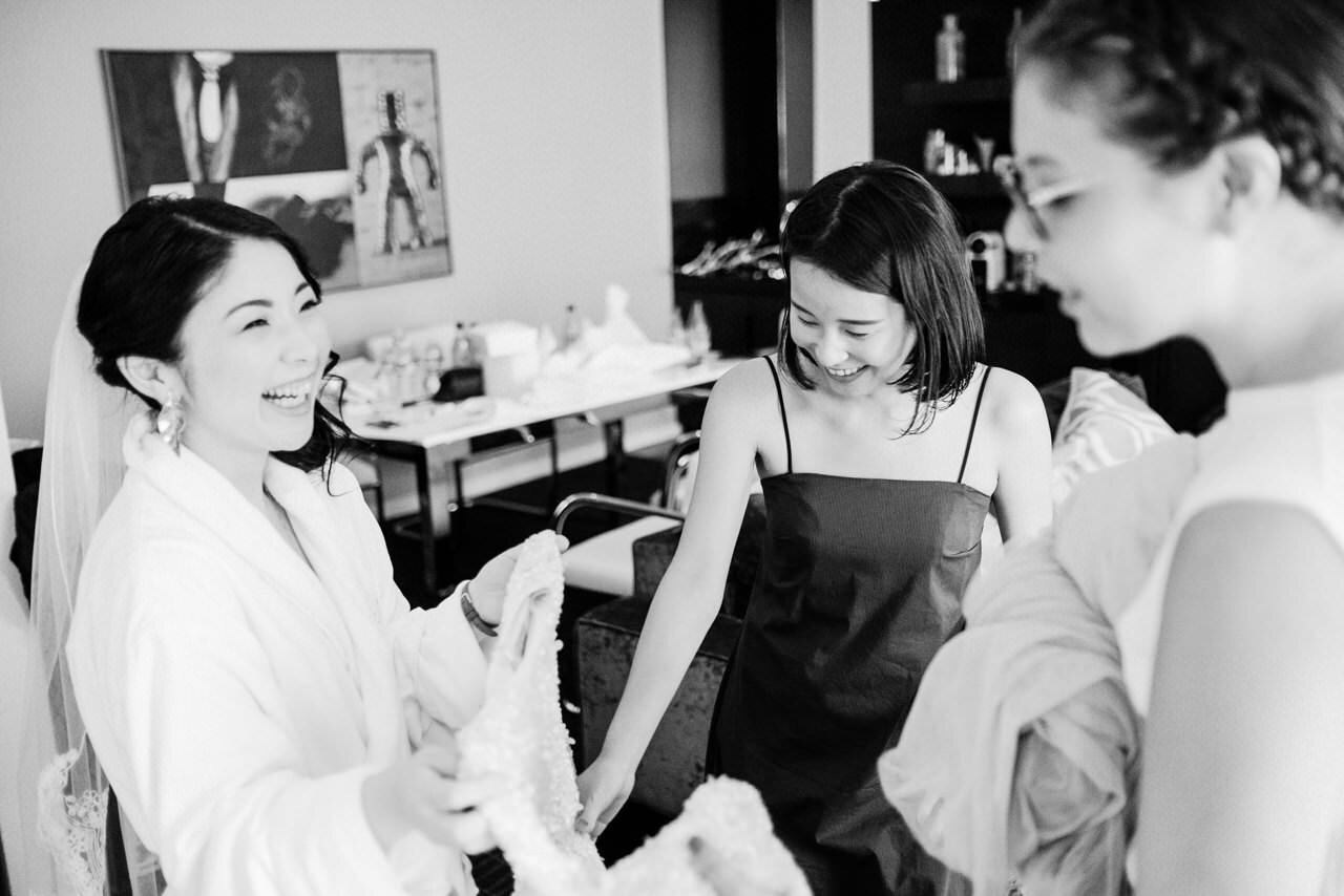  Japanese bride laughing with bridesmaids during candid moment 