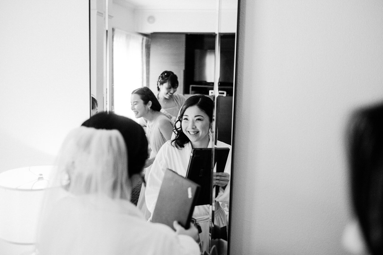  Bride from Japan smiling in hotel mirror in robe 