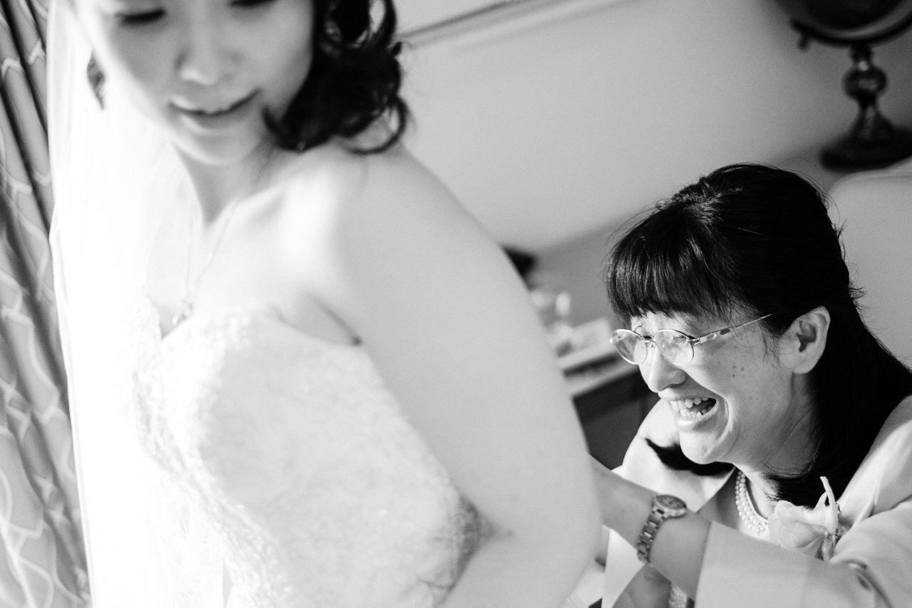  Bride's mother buttoning on wedding dress 