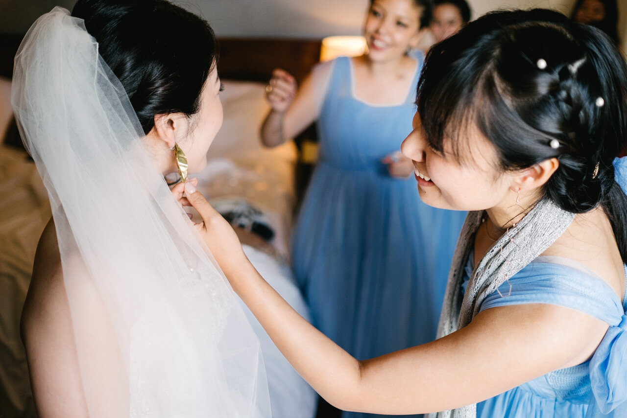  Bridesmaid inspects gold triangular earrings 