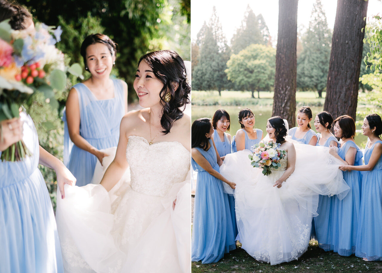  Bridesmaids in blue dresses hold bride's wedding dress in front of pond and fir trees 