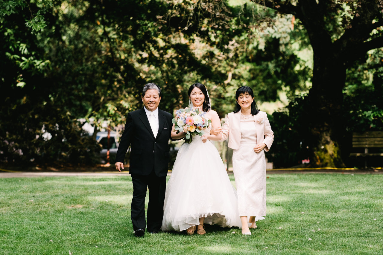  Japanese Bride smiles with father and mother as they approach the wedding on a lawn at crystal springs 