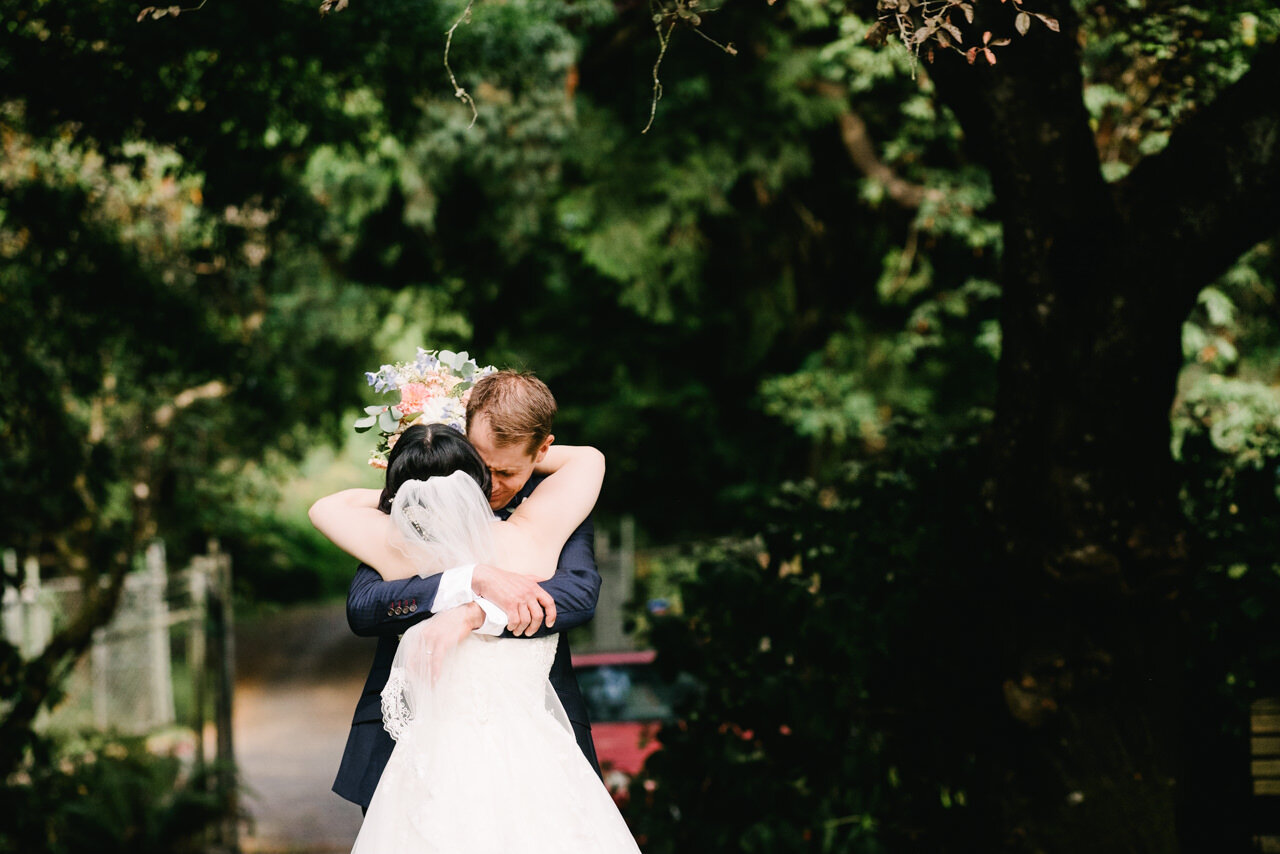  Groom hold bride emotionally after wedding ceremony under trees 