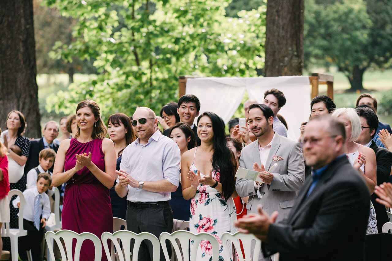  Wedding guests smile while watching bride and groom leave the ceremony 