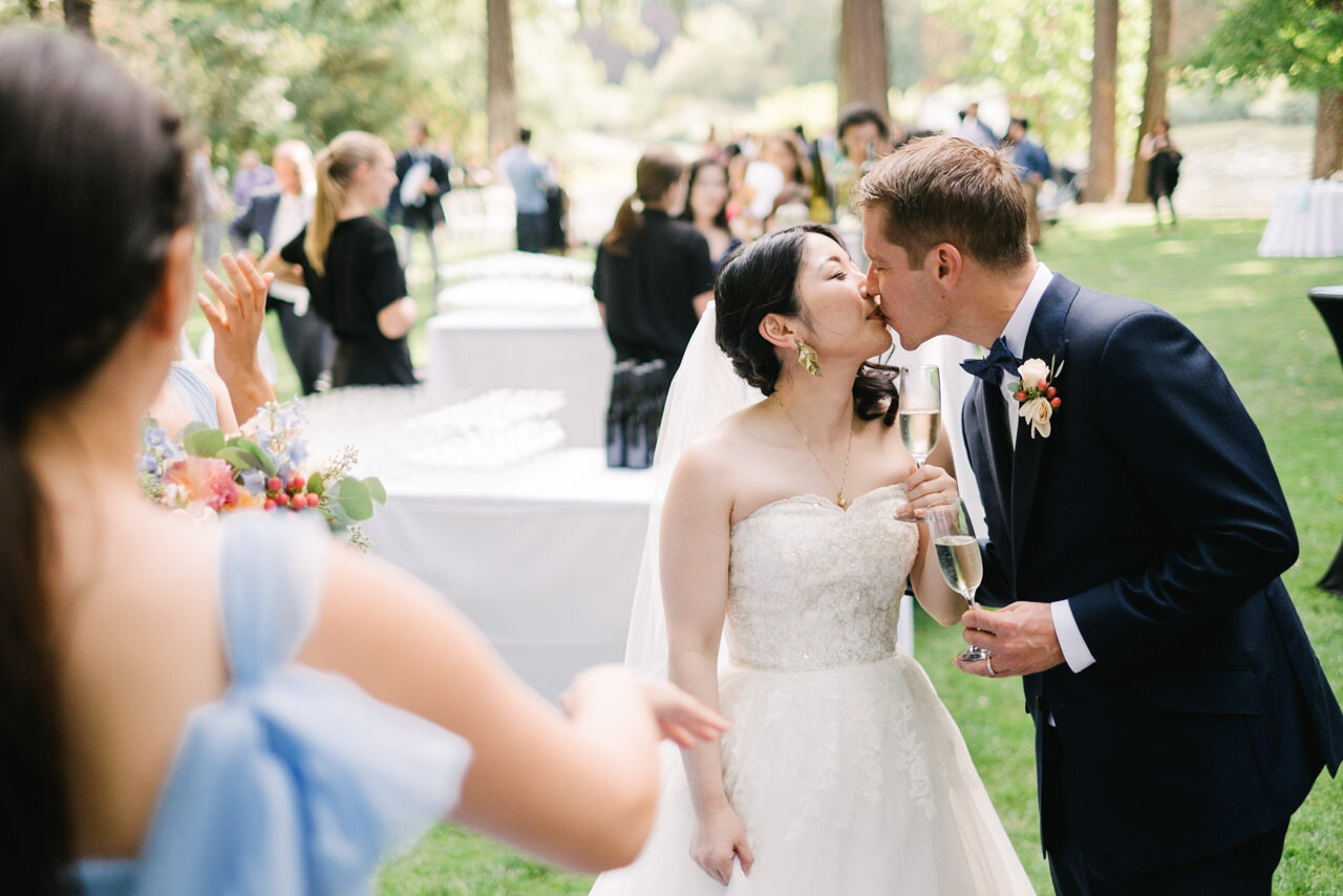  Bride and groom toast with champagne glasses and kiss at outdoor wedding reception 