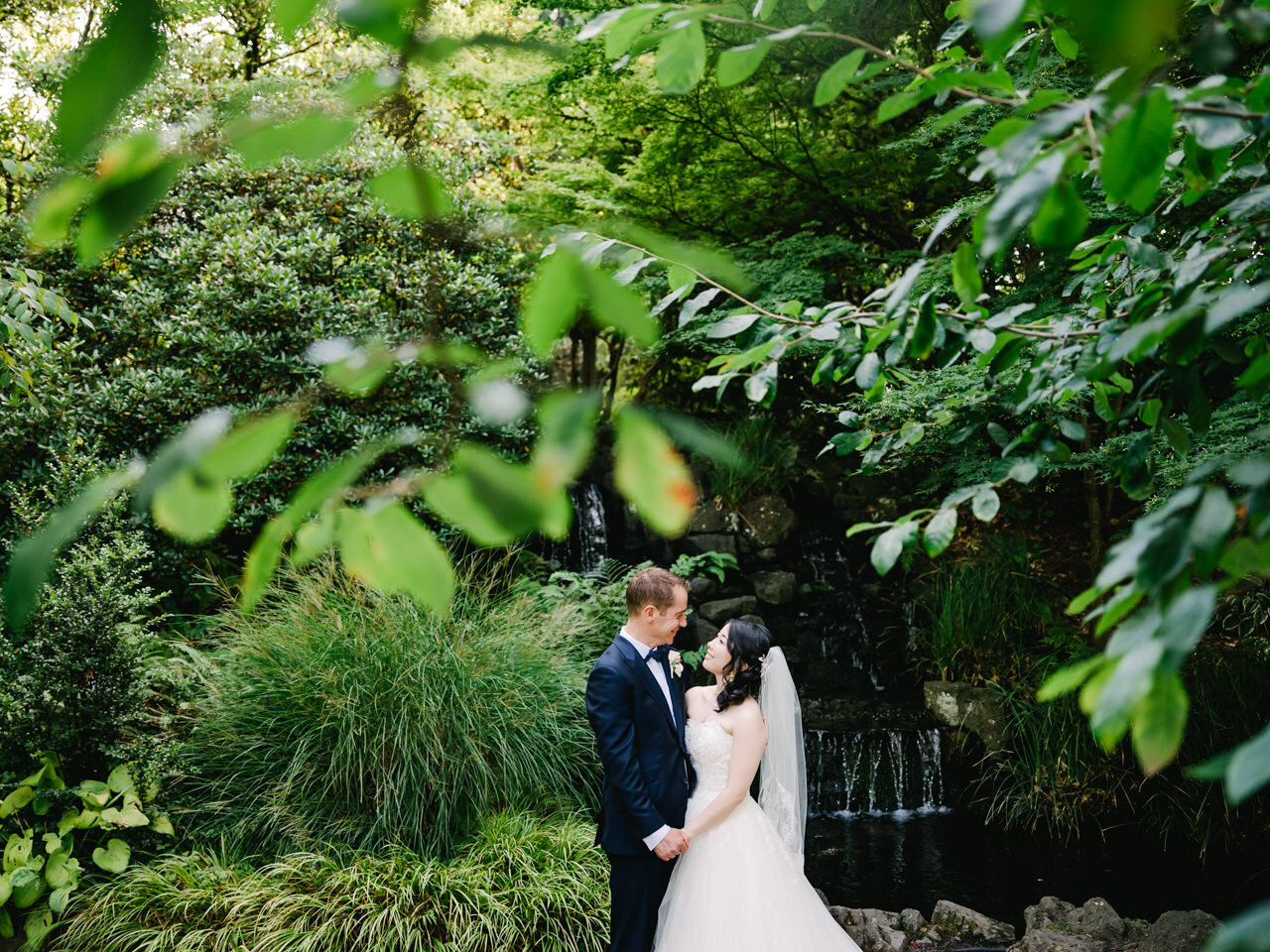  Bride and groom under trees and pond waterfall 