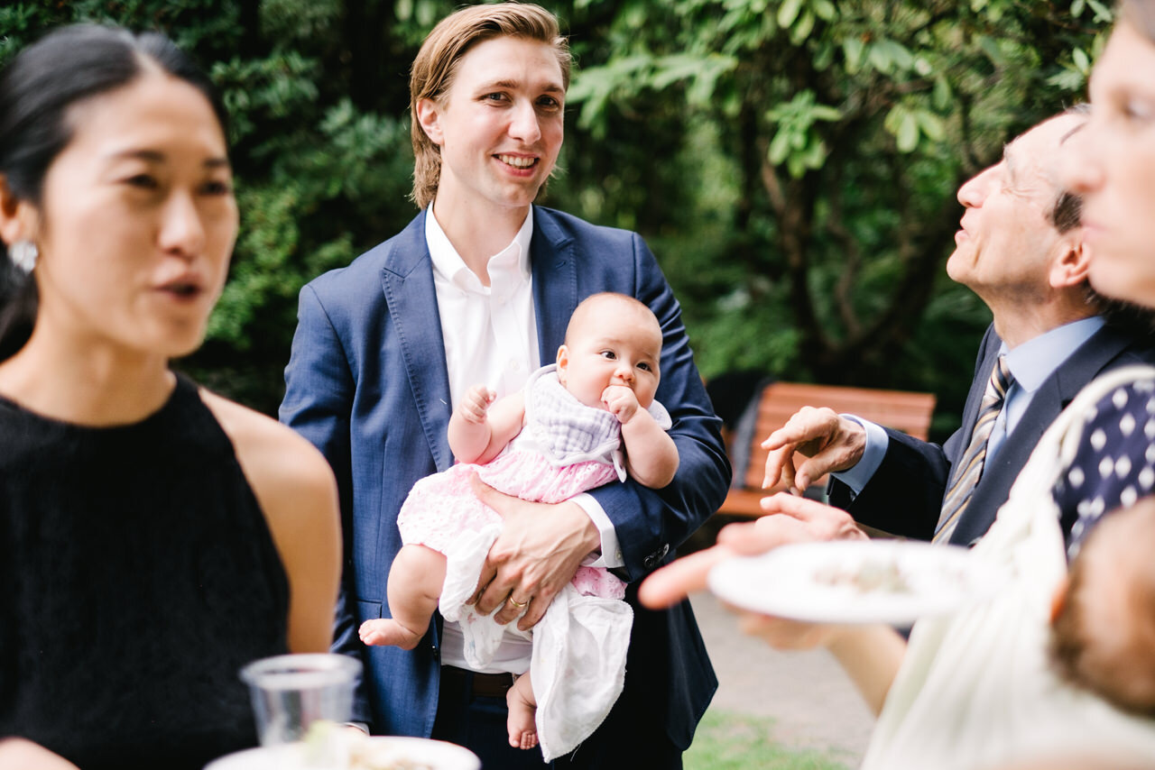  Wedding guest in blue jacket holds baby 