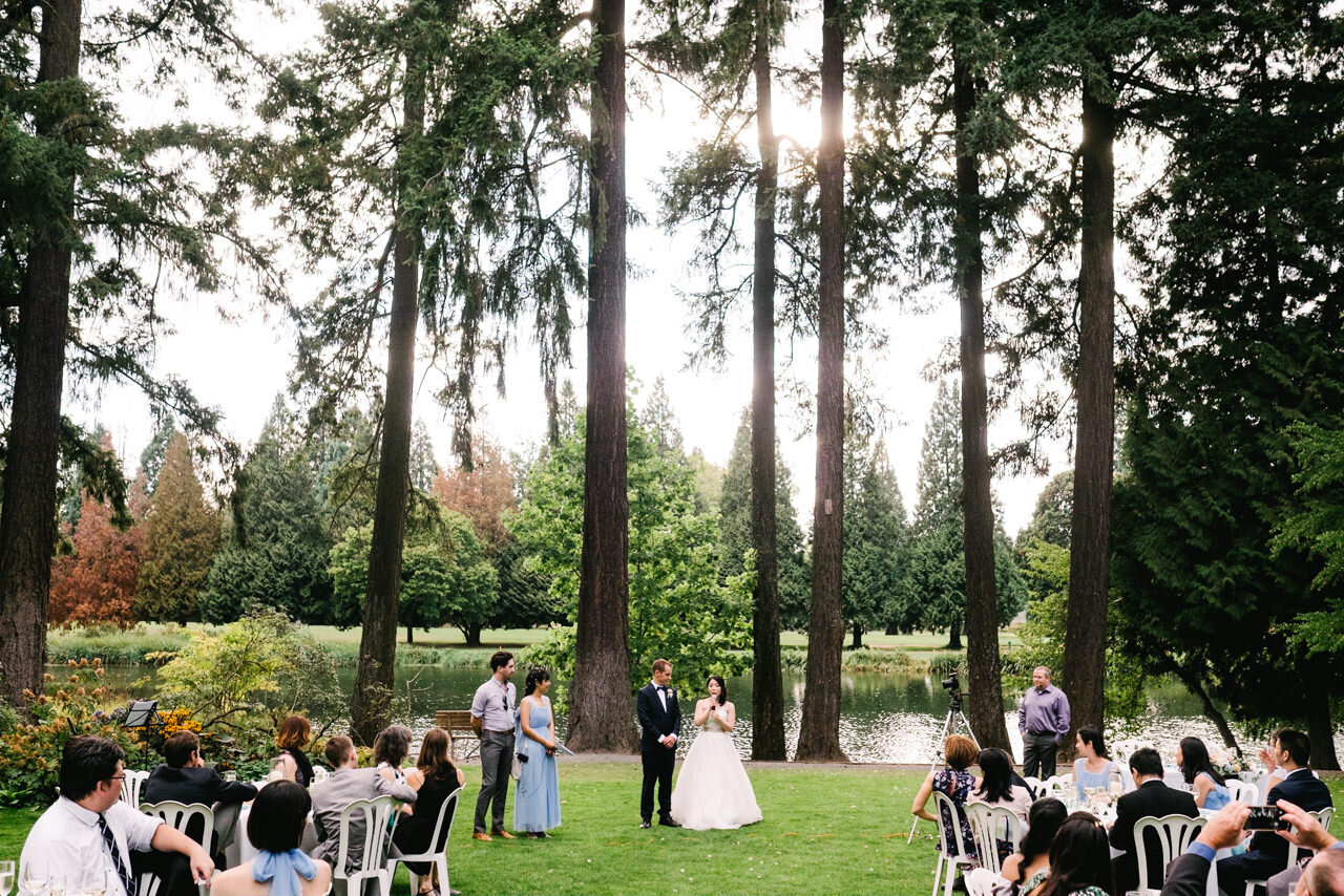  Bride and groom say welcome toast under tall fir trees and pond in portland 