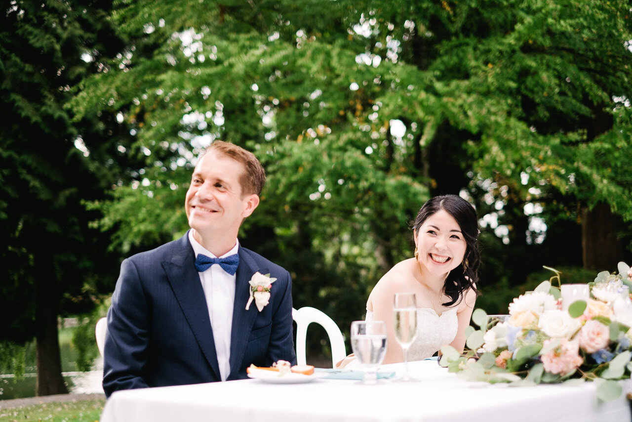  Bride and groom laugh at wedding toast with bouquet on the table 