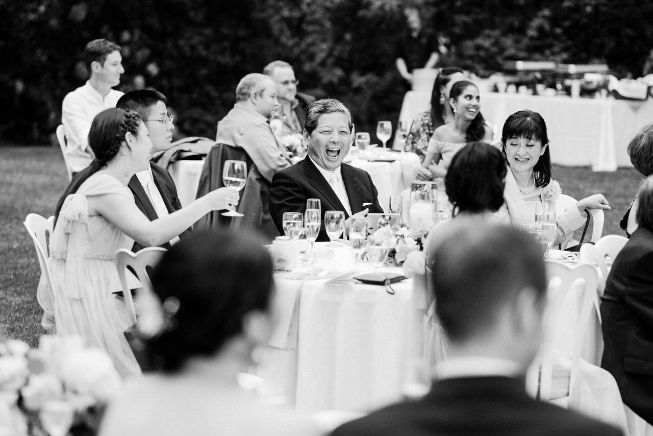  Father of bride laughs during toasts in outdoor reception tables 