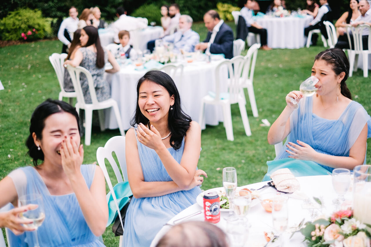  Bridesmaids in blue dresses cover their mouth laughing 