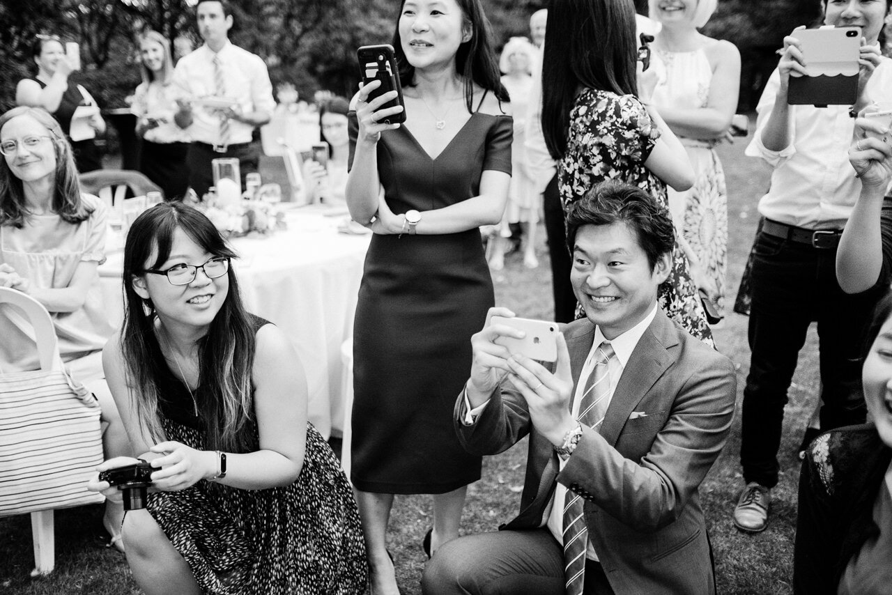  Wedding guest take iPhone photos of cake cutting 