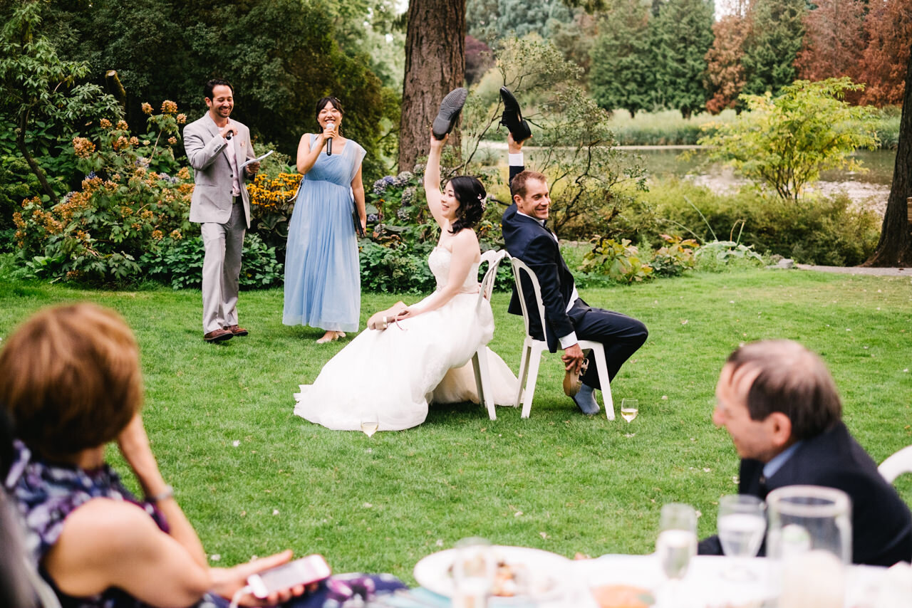  Bride and groom play shoe game in front of wedding guests on lawn at crystal springs garden 