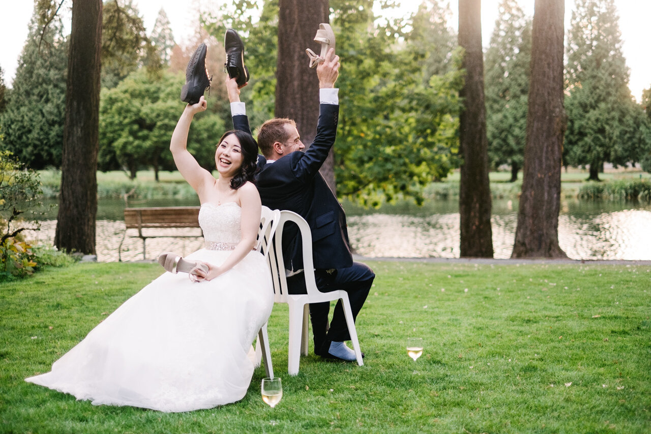  Bride and groom hold up both shoes during wedding shoe game in outdoor reception 