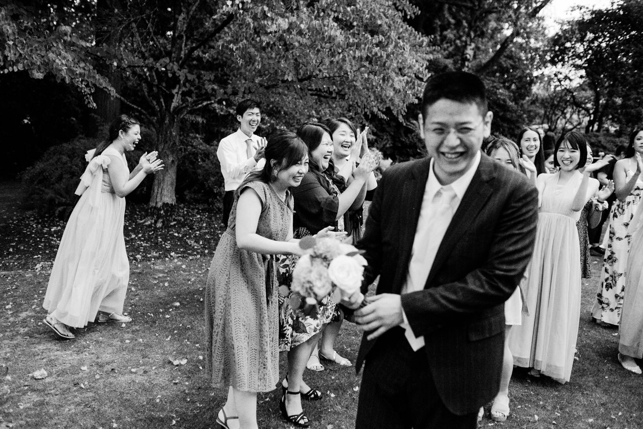  Wedding guests laugh as brother holds bouquet after toss 