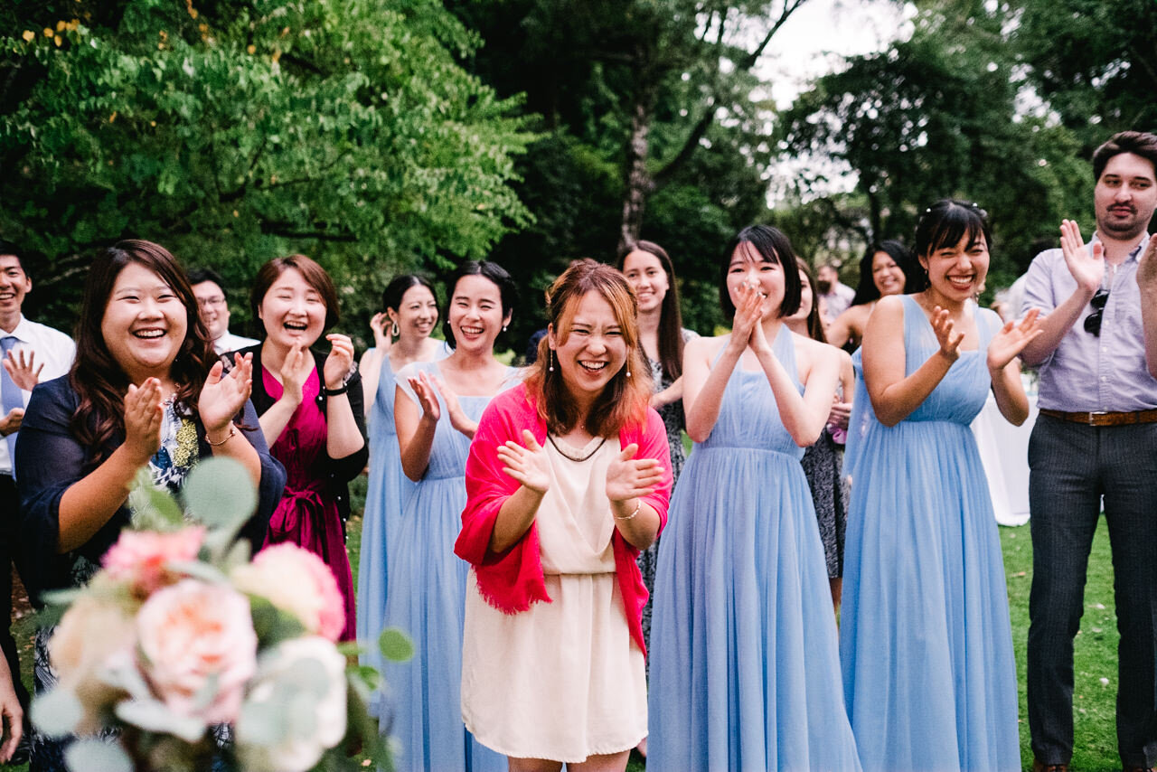  Wedding guest in pink shawl and bridesmaids clap after wedding bouquet toss 