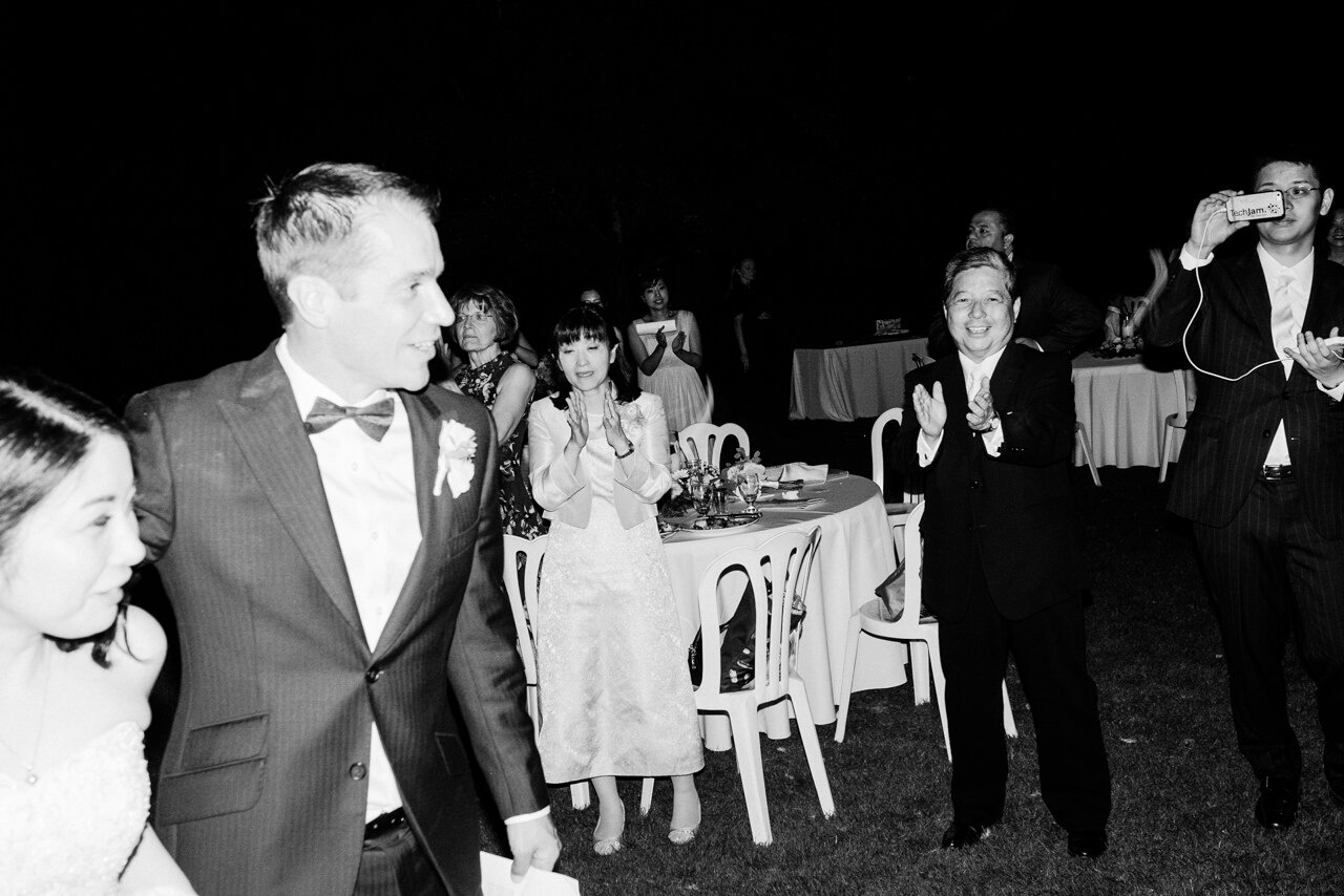  Bride and groom leave wedding while guests clap at night time 