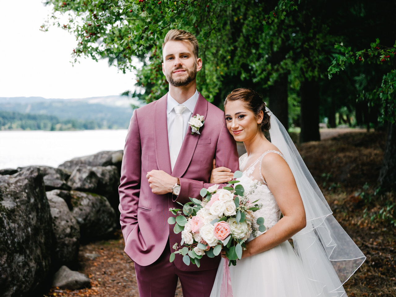  Bride holds groom's arm in portrait by Columbia river 