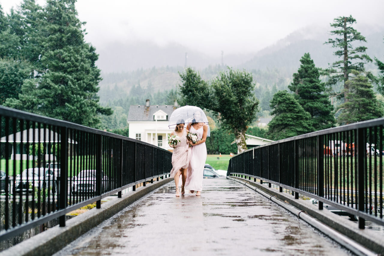  Bridesmaids in peach walk across rainy bridge at cascade locks 