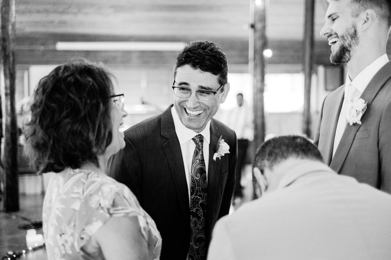  Candid moment of father laughing with groom and guests 