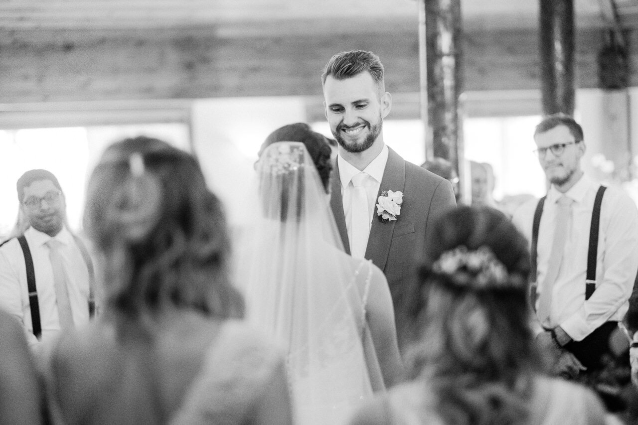  Groom smiling at bride in black and white photo during wedding 