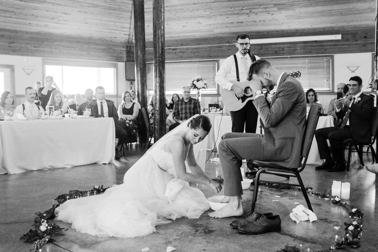  Bride drying her hands after washing groom's feet during foot washing ceremony 