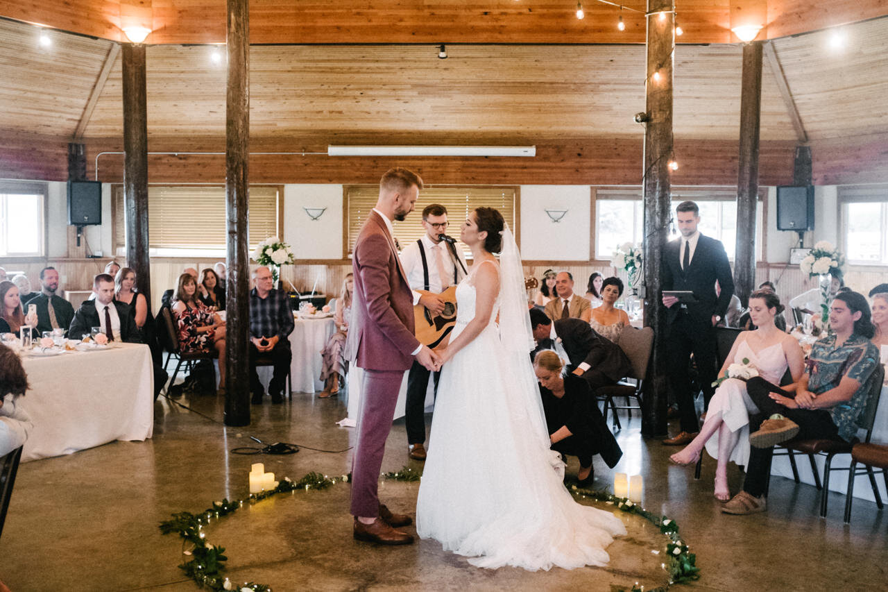  Bride and groom listen to guitar player while holding hands 