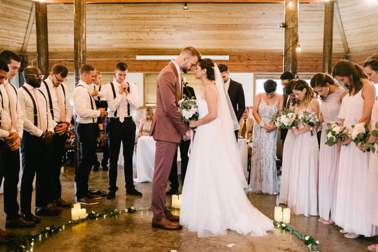  Bride and groom place heads together during prayer during wedding ceremony 