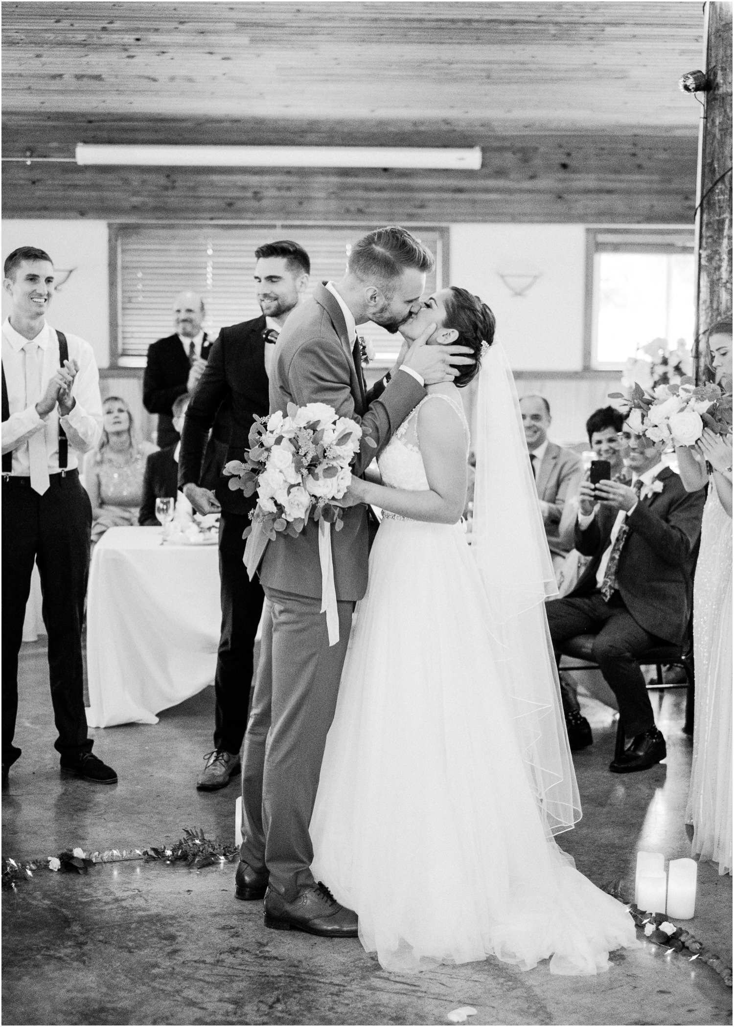  Bride and groom kiss in black and white photo after wedding ceremony 