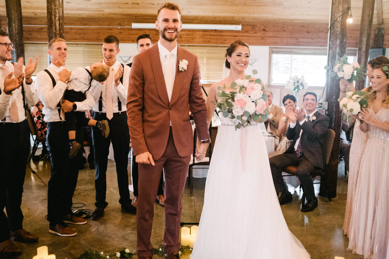  Bride with pink and white bouquet holds groom hands after pronounced just married 