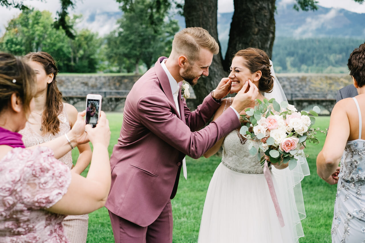  Groom pinches bride's cheeks while guests take iPhone photos 