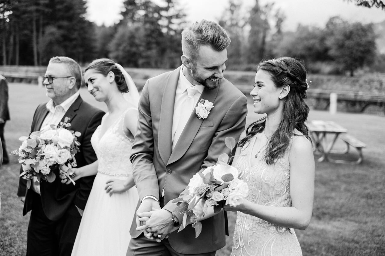  Groom and bride's sister smile together during wedding portraits 