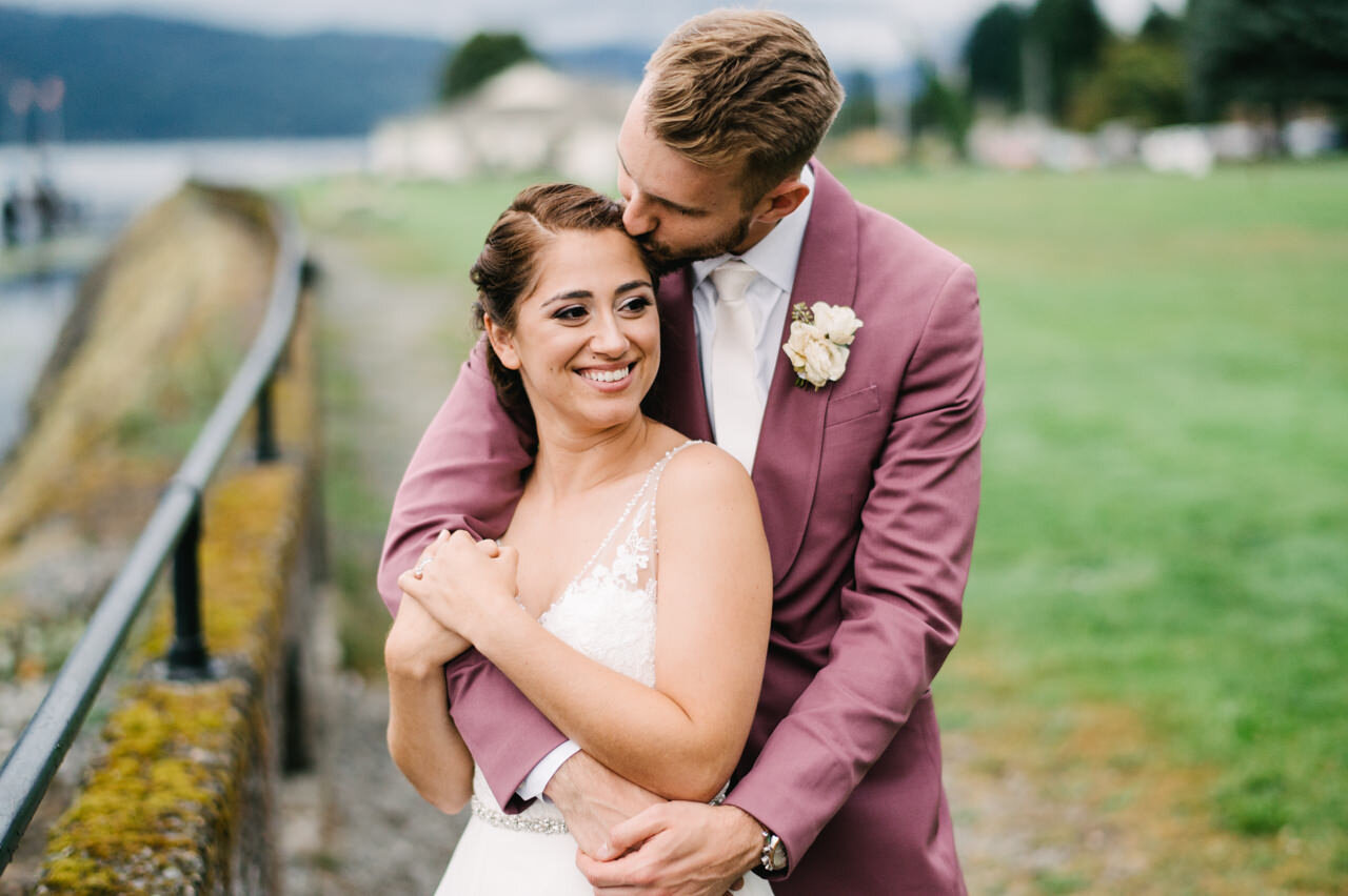 Groom in purple suit kissing bride at cascade locks marine park wedding 