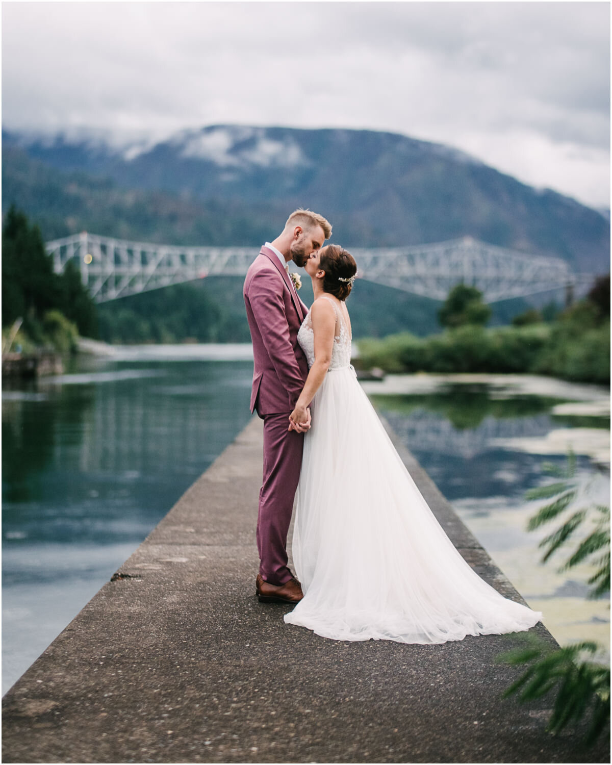  Bride kisses groom with the Columbia gorge and bridge of the gods behind them 